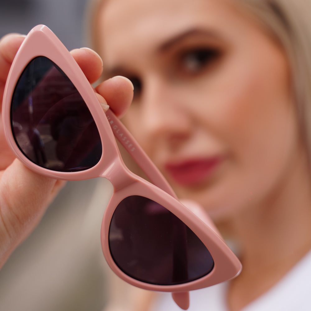 Milah Sunglasses by Glamour Glasses featuring a bold salmon pink cat eye frame - held in hand shot